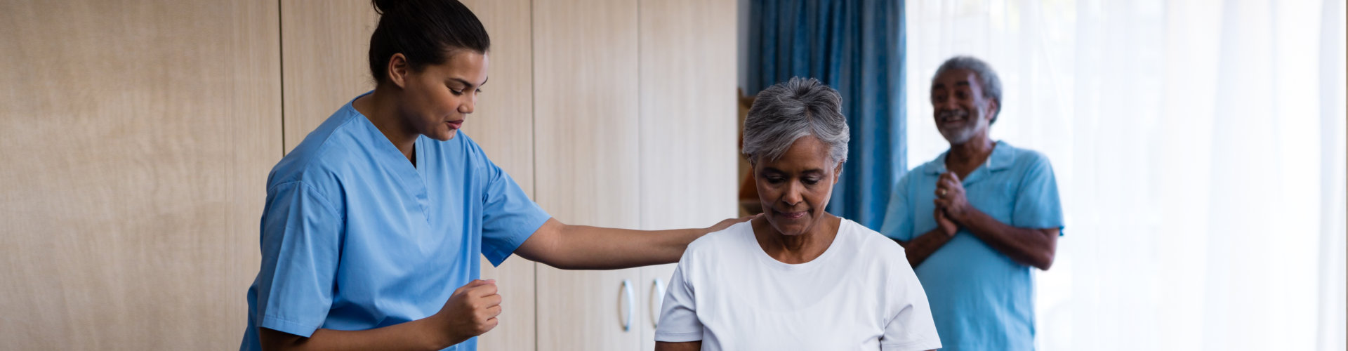 nurse helping a woman and a man cheering behind